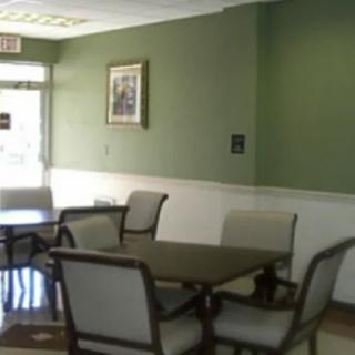 A dining area with green walls, featuring several tables and chairs.