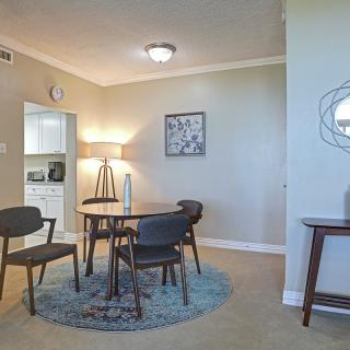 A modern dining room with a round table and stylish chairs, complemented by a floor lamp and wall artwork in a neutral color palette.