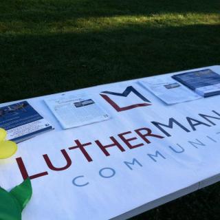 A community event table with a banner displaying informational materials outdoors.