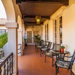A charming patio with arches and outdoor seating, featuring tables and chairs surrounded by plants.