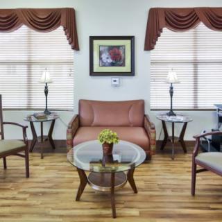 A cozy living room with a sofa, chairs, and a coffee table, complemented by stylish lamps and wood flooring.