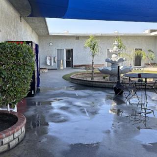 A tranquil courtyard featuring a fountain, vending machine, and outdoor seating under a blue awning.