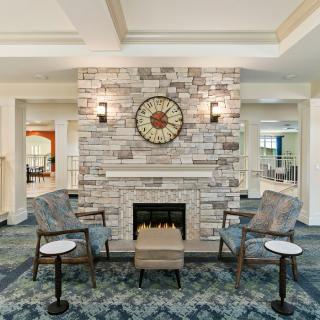 A cozy seating area with a brick fireplace and decorative clock in a modern living room.