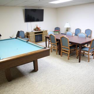 A spacious game room featuring a pool table and a cozy dining area, complete with a television.