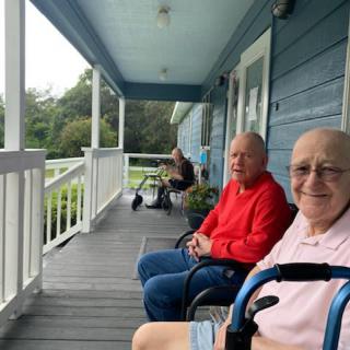 Elderly individuals relaxing on a porch in the daytime.