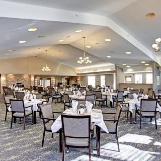 A spacious dining area with neatly arranged tables and chairs, featuring elegant chandeliers.