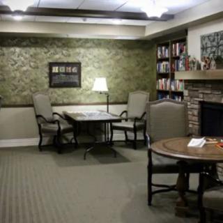 Cozy library corner with seating around a fireplace and bookshelves.
