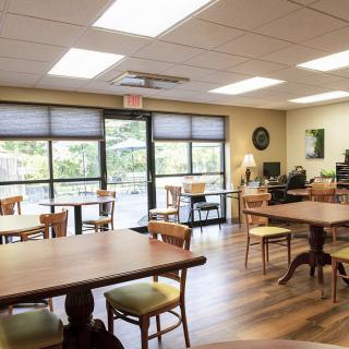 A cozy cafe interior with wooden tables and chairs, featuring large windows and a warm atmosphere.