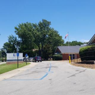 A clear day at a building with a parking lot and trees.