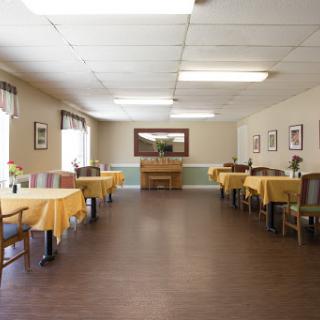 A spacious dining room featuring tables with yellow tablecloths, designed for casual dining.