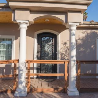 A residential house entrance featuring a decorative front door with white columns and a wooden porch.