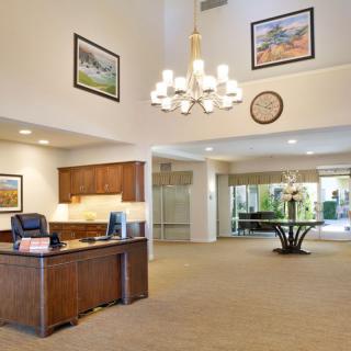 Elegant lobby with a chandelier, wooden desk, and artwork on the walls.