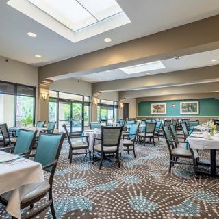 A spacious and elegantly designed dining area with tables and chairs, featuring modern lighting and large windows.