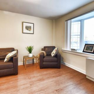 A cozy living room with two brown chairs and a side table near a large window.