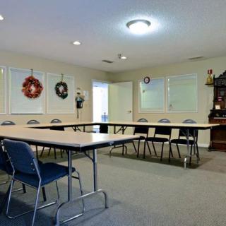 A meeting space with arranged tables and chairs, decorated with wreaths on the walls.