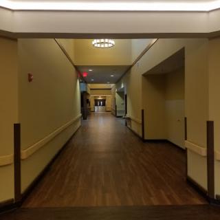A long, empty hallway with warm lighting and wooden flooring.