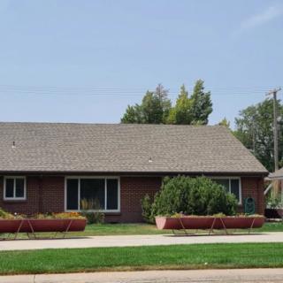 A single-story brick house with a well-maintained front yard in a suburban setting.