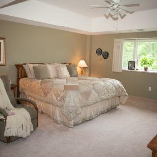 A cozy bedroom with a large bed, soft lighting, and a window letting in natural light.