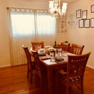 A cozy dining room with a wooden table, chairs, and a chandelier.