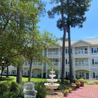 A scenic view of a residential building with a fountain and a well-maintained garden.