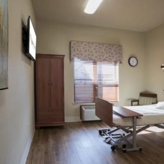 A clean and well-lit hospital room with a bed, cabinet, and window.