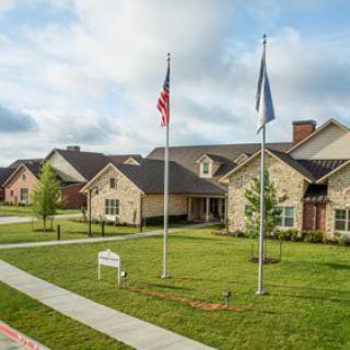 A suburban neighborhood with neatly arranged houses and flags displayed on a sunny day.