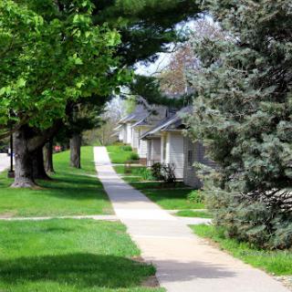 A peaceful neighborhood path lined with trees and well-manicured grass.