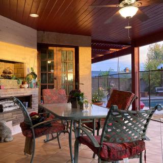 A cozy outdoor patio with a glass table, chairs, and a fireplace, perfect for evening relaxation.