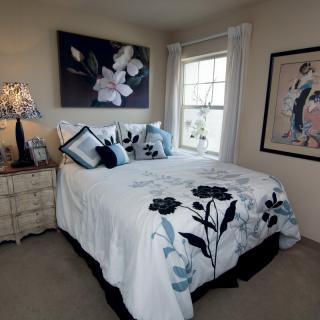 A cozy bedroom with floral decor and artwork on the walls.