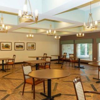 An empty dining area with tables and chairs arranged under stylish chandeliers.