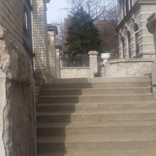 A view of stone steps leading up, flanked by a classic architectural structure.