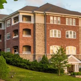 A three-story brick apartment building with a well-maintained lawn.