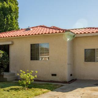 A single-story house with a red-tiled roof and a small front yard.