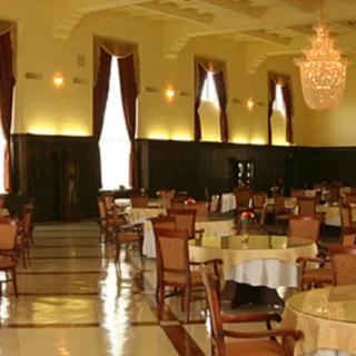An elegant restaurant dining room with a chandelier and neatly arranged tables and chairs.
