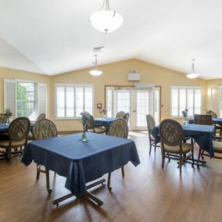 A spacious dining area with tables and chairs, illuminated by natural light from large windows.