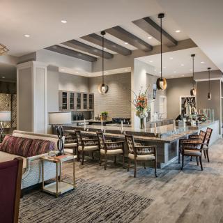 A spacious and modern kitchen with an open layout, featuring a large island, bar stools, and elegant pendant lights.