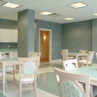 An empty dining area with modern furniture and a kitchenette.