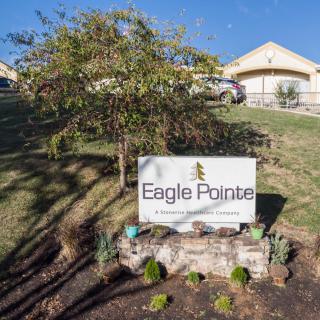 Sign for Eagle Pointe with landscaping and building in the background on a sunny day.
