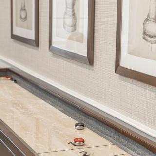 An indoor shuffleboard table with framed artwork on the wall.