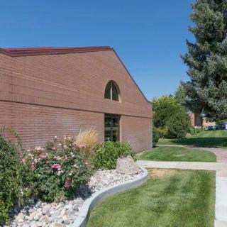 A brick building with landscaped surroundings, including green grass and bushes under a clear blue sky.