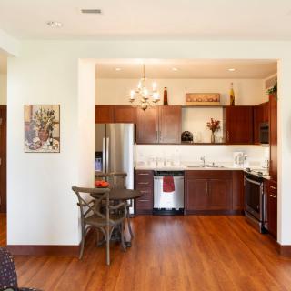 A modern kitchen with wood flooring, stainless steel appliances, and a cozy dining area.