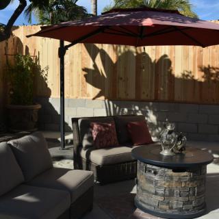 A cozy outdoor patio with seating and a fire pit under an umbrella.
