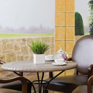 A cozy patio setting featuring a small round table with chairs, adorned with a tea set and potted plant.