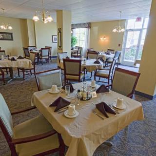 A neatly arranged dining room with several tables and chairs, set for service.