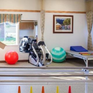 A physical therapy room equipped with an exercise bike and therapy balls.