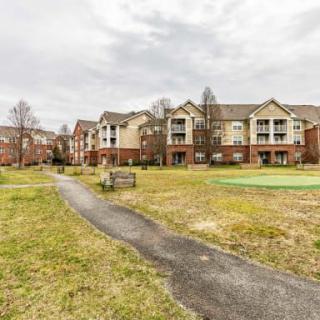 An apartment complex with a central pathway and surrounding grassy areas, under an overcast sky.