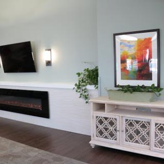 A modern living room featuring a sleek TV, a decorative fireplace, and vibrant artwork.