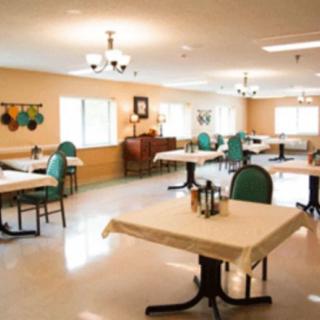 An empty dining room with neatly arranged tables and chairs, well-lit with natural and artificial lighting.