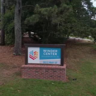 An outdoor sign for a center surrounded by trees.