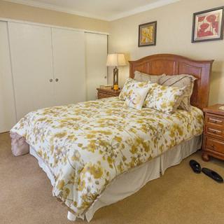 A cozy bedroom with a floral-patterned bedspread, wooden furniture, and decorative wall art.